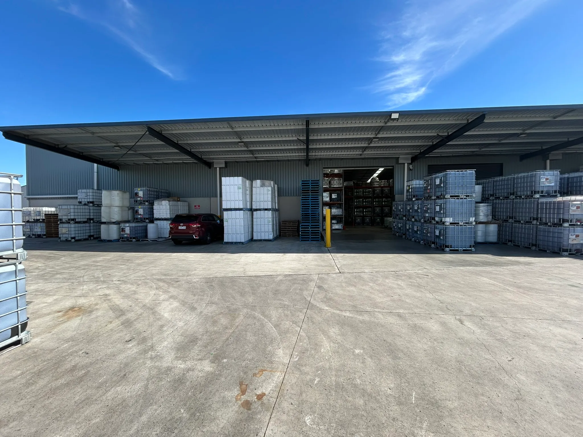 Tollman warehouse — covered loading bay with palletised IBC totes